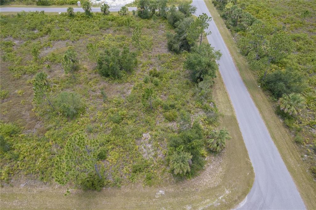 An aerial view shows a vacant, wooded corner lot bordered by two paved roads — 219 GASTIN STREET, PORT CHARLOTTE, FL