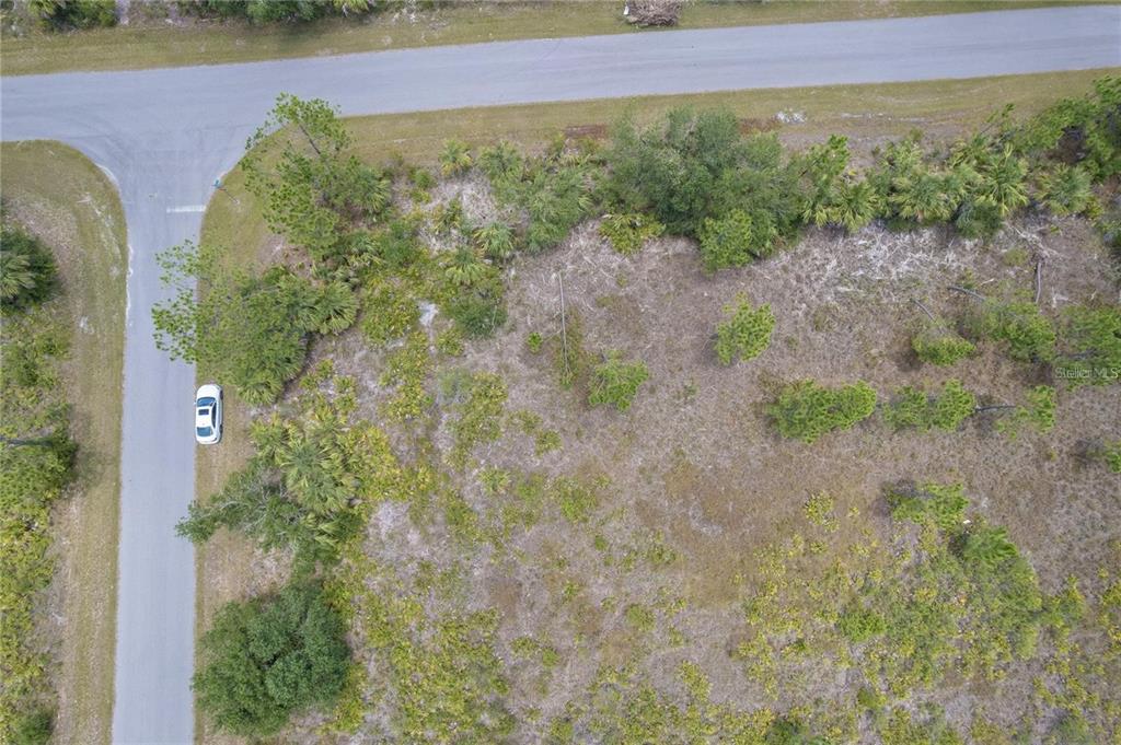 An aerial view shows a vacant, wooded corner lot bordered by two paved roads — 219 GASTIN STREET, PORT CHARLOTTE, FL