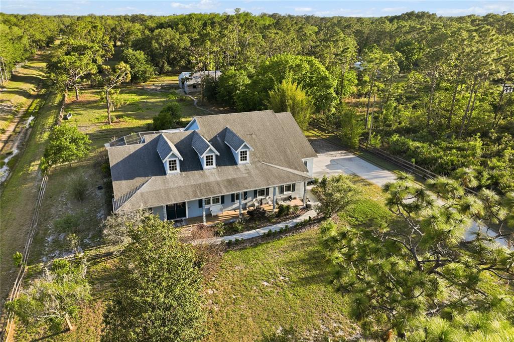 An aerial view of a two-story house with three dormers surrounded by wooded land — 19802 PEABODY STREET, ORLANDO, FL
