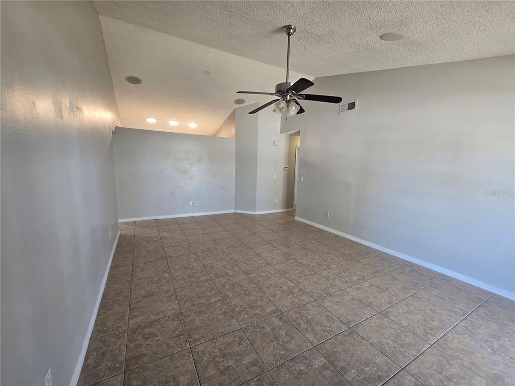 A spacious room with vaulted ceilings, a ceiling fan, and light-colored tile flooring — 12109 CLEARBROOK COURT, RIVERVIEW, FL