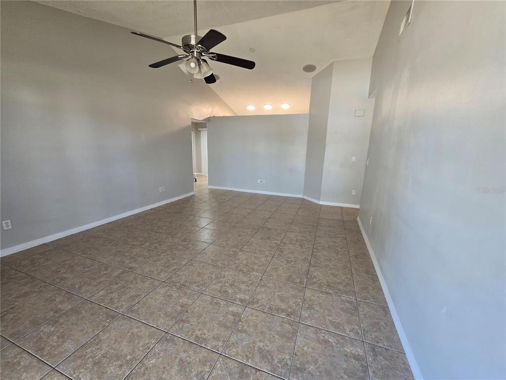 A spacious room with light gray walls, tile flooring, and a vaulted ceiling with a fan — 12109 CLEARBROOK COURT, RIVERVIEW, FL