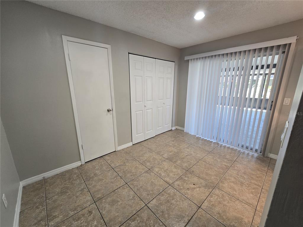 A room with tile flooring, a single door, a double-door closet, and vertical window blinds — 12109 CLEARBROOK COURT, RIVERVIEW, FL