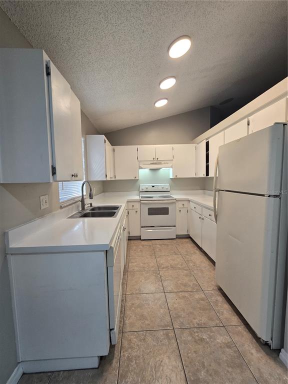 A galley-style kitchen features white cabinets, white appliances, and light-colored tile flooring — 12109 CLEARBROOK COURT, RIVERVIEW, FL