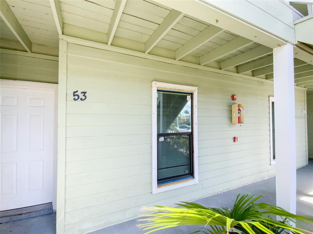 A light green exterior wall features a white door, a window, and a fire extinguisher — 455 ALT 19 S UNIT 53, PALM HARBOR, FL