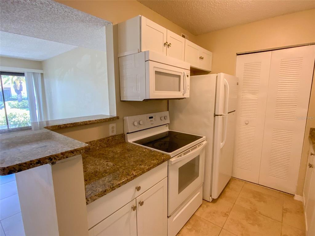 A kitchen features white cabinets, white appliances, and granite countertops — 455 ALT 19 S UNIT 53, PALM HARBOR, FL