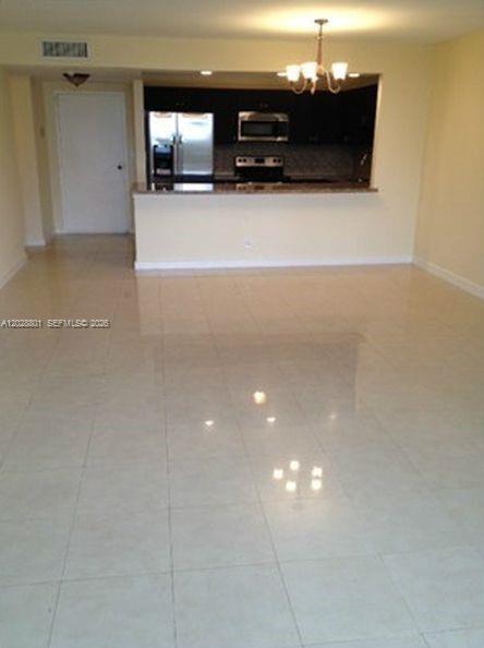 An open-concept living area with light tile flooring leads to a kitchen with dark cabinets — 2500 Parkview Dr # 307, Hallandale Beach FL 33009, HALLANDALE BEACH, FL
