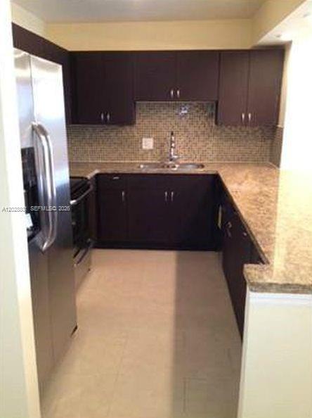 A kitchen with dark wood cabinets, granite countertops, stainless steel appliances, and a tiled backsplash — 2500 Parkview Dr # 307, Hallandale Beach FL 33009, HALLANDALE BEACH, FL