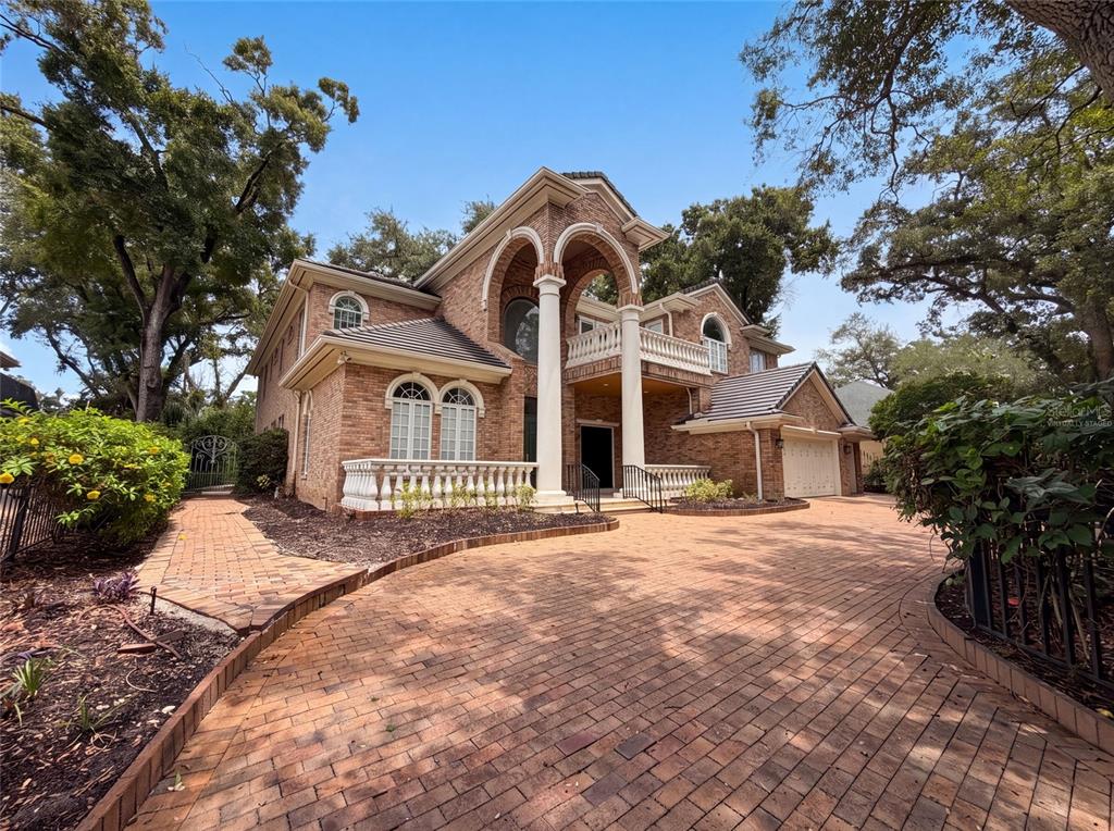 A two-story brick house features a grand arched entryway with white columns and a balcony — 4407 W DALE AVENUE, TAMPA, FL
