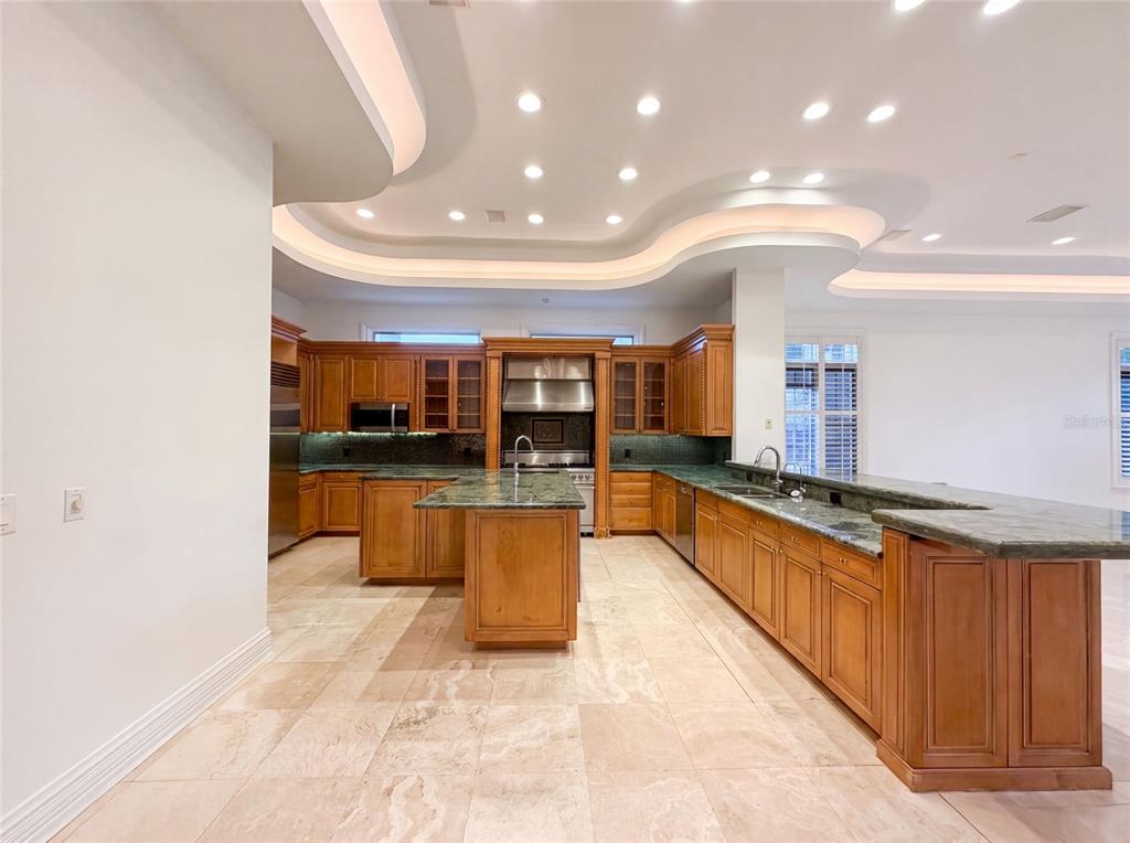 A kitchen features wood cabinetry, green stone countertops, a central island, and recessed ceiling lighting — 4407 W DALE AVENUE, TAMPA, FL