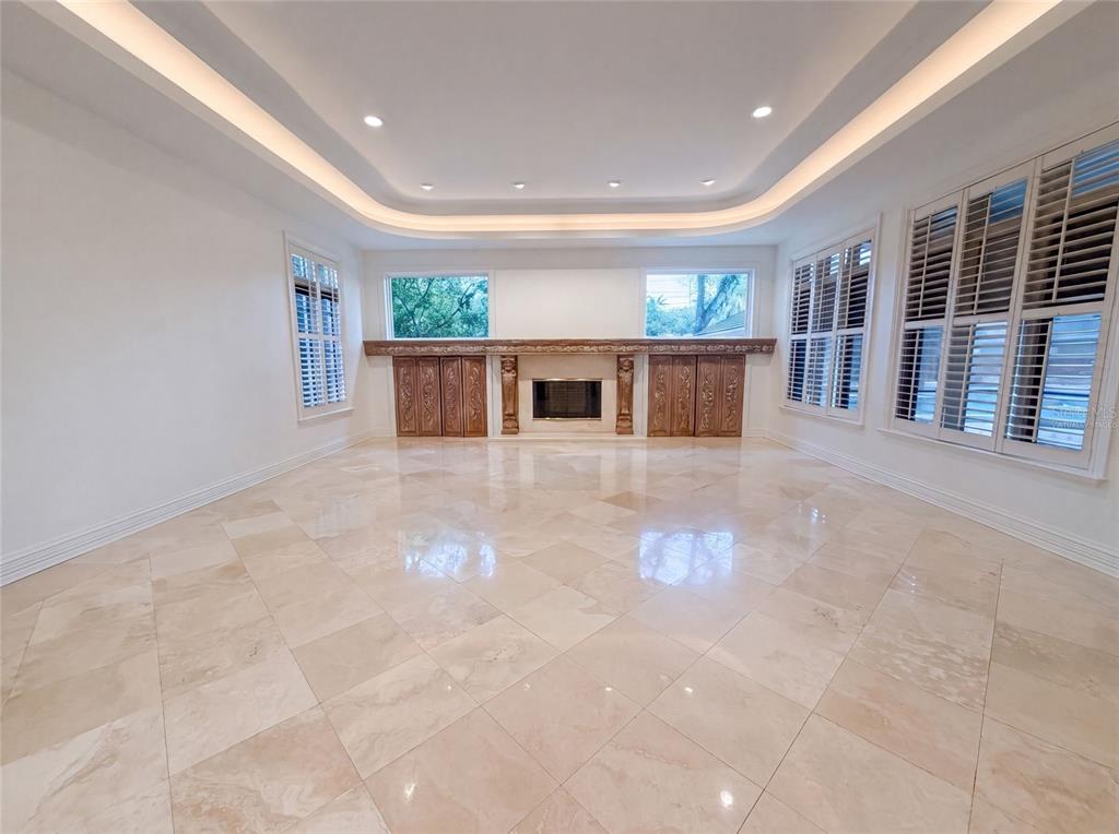 A spacious living room features a fireplace, tile flooring, recessed tray lighting, and plantation shutters — 4407 W DALE AVENUE, TAMPA, FL
