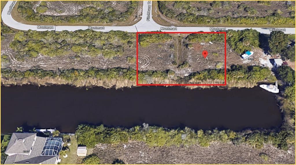An aerial view shows a vacant, rectangular waterfront lot outlined in red along a canal — 14315 MONTMARTE AVENUE, PORT CHARLOTTE, FL