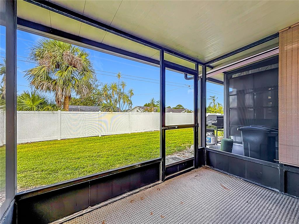 A screened-in porch overlooks a grassy backyard enclosed by a white vinyl fence — 2474 ENTERPRISE ROAD UNIT 3, CLEARWATER, FL