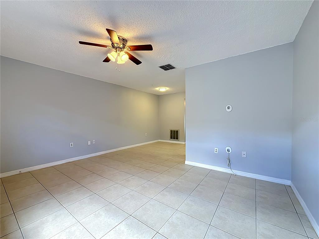 An empty room with light gray walls, beige tile flooring, and a ceiling fan — 2474 ENTERPRISE ROAD UNIT 3, CLEARWATER, FL