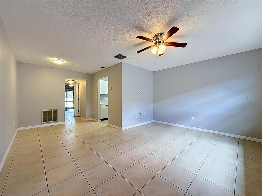An empty living room features light-colored tile flooring, gray walls, and a ceiling fan — 2474 ENTERPRISE ROAD UNIT 3, CLEARWATER, FL