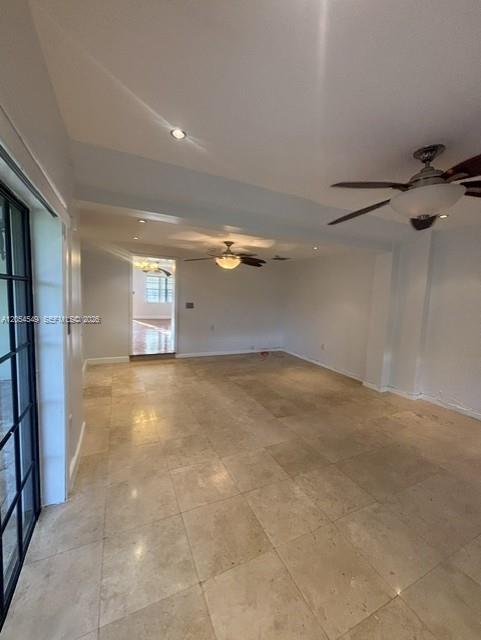 An interior view of a spacious room with beige tile flooring and two ceiling fans — 14590 NW 10th Ave, Miami FL 33168, MIAMI, FL