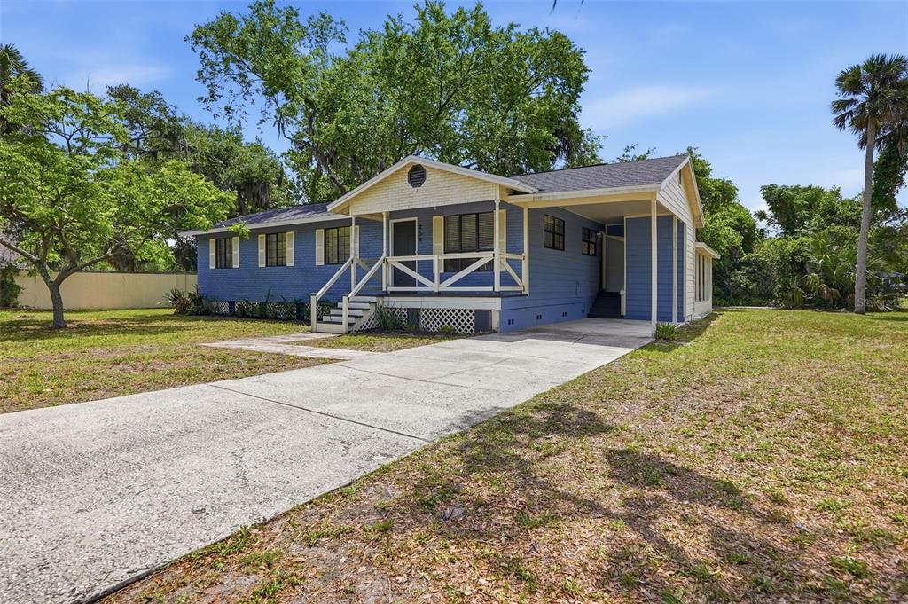 A blue, single-story house with a front porch, carport, and concrete driveway sits on grass — 254 OLEANDER PLACE, ORMOND BEACH, FL