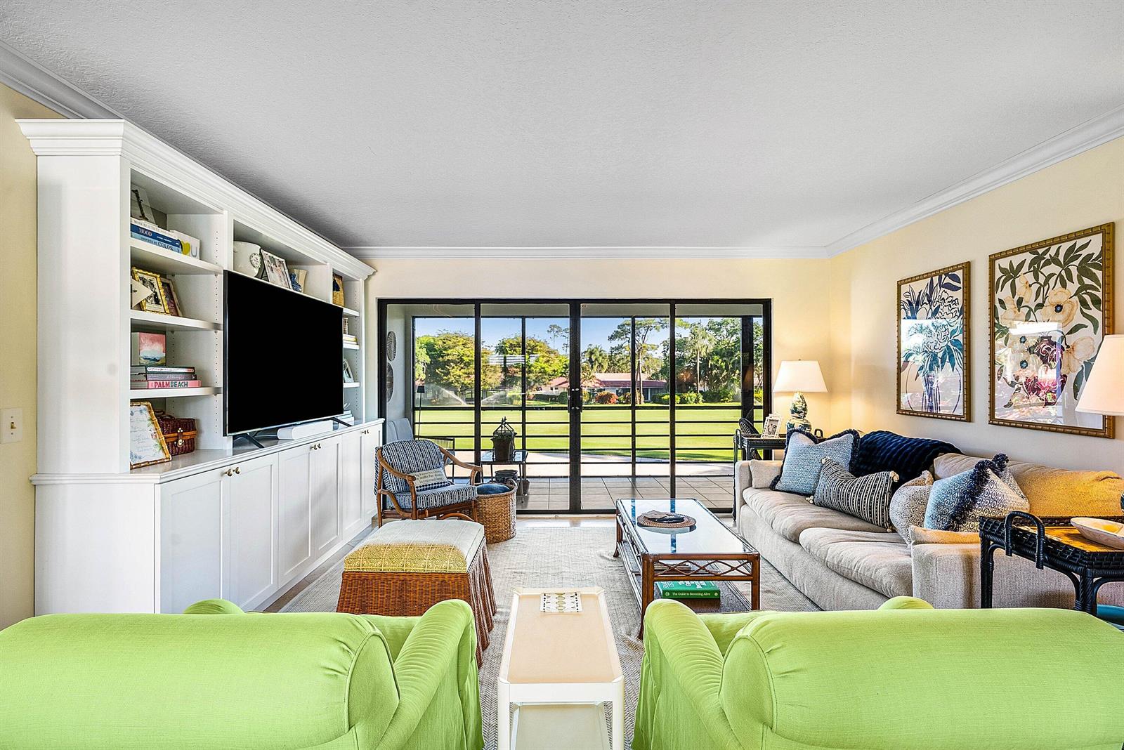A living room features a built-in media center, two green armchairs, and sliding glass doors — 4595 Kittiwake Court, Boynton Beach FL 33436, BOYNTON BEACH, FL