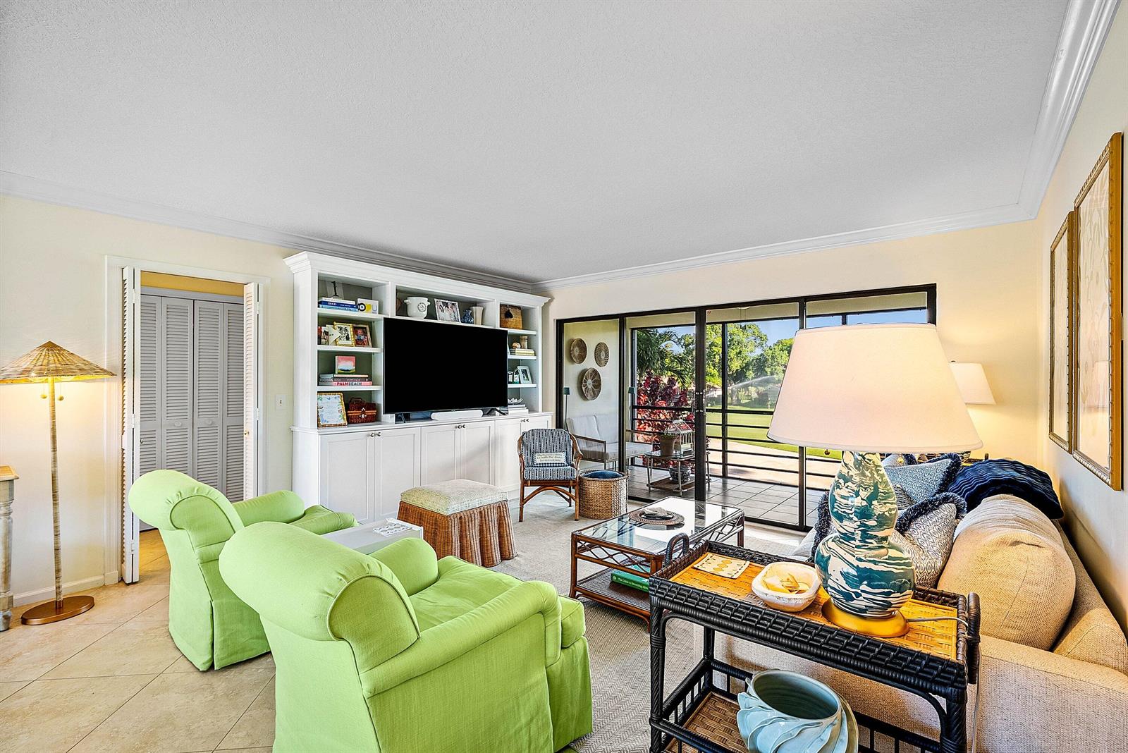 A living room features lime green armchairs, a white built-in media unit, and sliding glass doors — 4595 Kittiwake Court, Boynton Beach FL 33436, BOYNTON BEACH, FL