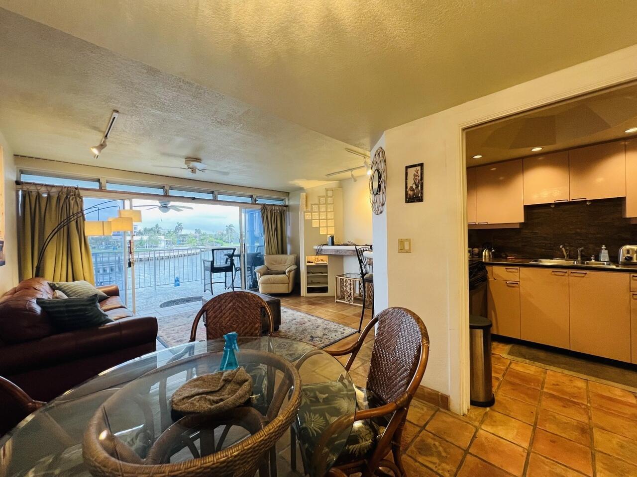 A dining area and living room with a view of a canal through sliding doors — 55 NE Spanish Trail # 2040, Boca Raton FL 33432, BOCA RATON, FL
