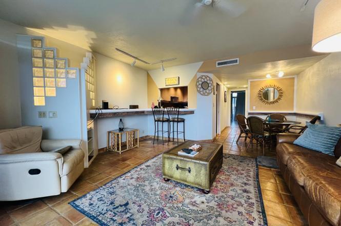 A living room with tile floors, a leather sofa, a glass block wall, and dining area — 55 NE Spanish Trail # 2040, Boca Raton FL 33432, BOCA RATON, FL