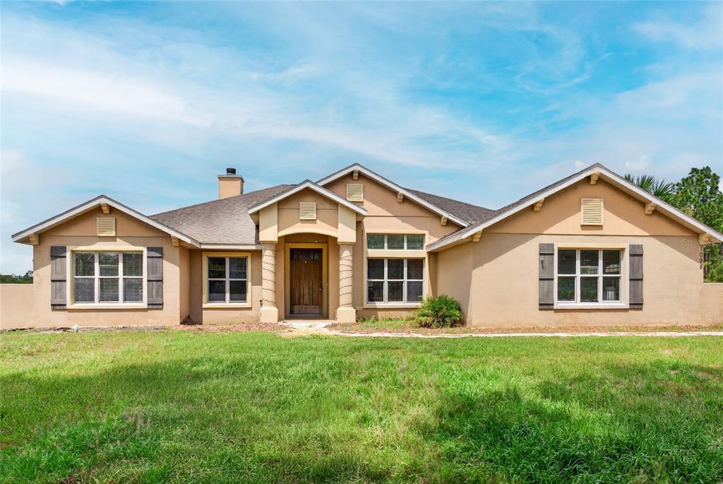 A single-story tan stucco house with a gabled roof and a covered front entryway — 1098 NW 165TH COURT ROAD, DUNNELLON, FL