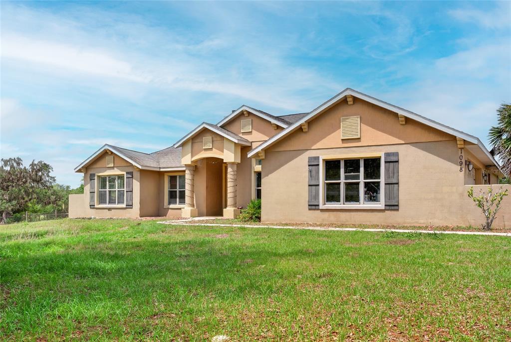 A single-story tan stucco house with a gabled roof and a front-facing window — 1098 NW 165TH COURT ROAD, DUNNELLON, FL