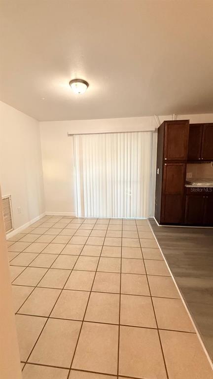 A room with beige tile flooring, a sliding glass door, and dark wood kitchen cabinets — 1604 WOODLYN DRIVE, LEESBURG, FL