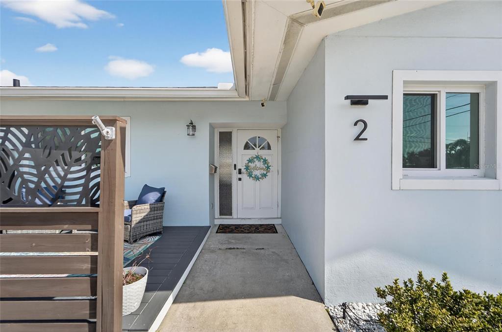The exterior of a light blue house features a front door, a window, and a deck — 2 79TH STREET S, ST PETERSBURG, FL