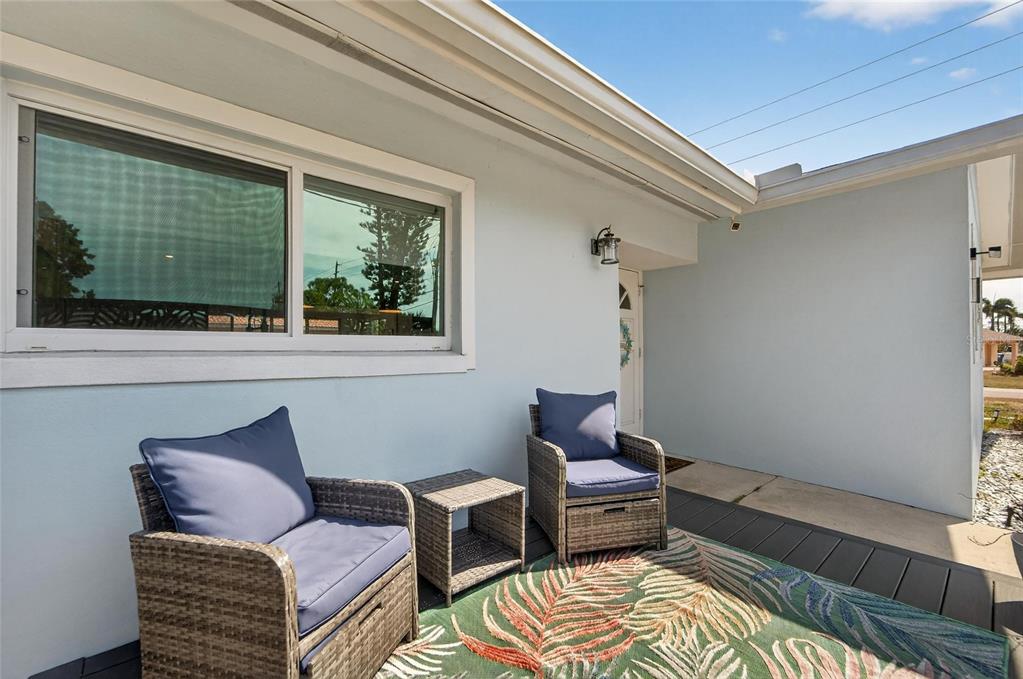 A patio features two wicker chairs, a small table, and a patterned rug — 2 79TH STREET S, ST PETERSBURG, FL