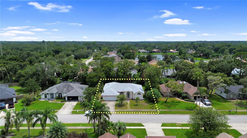 An aerial view shows a single-story house with a light-colored roof and a front driveway — 516 SUN LAKE DRIVE, PORT ORANGE, FL