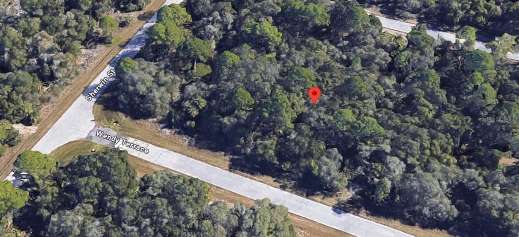 An aerial view shows a wooded, undeveloped lot marked by a red pin near a road — 1236 WENDY TERRACE, PORT CHARLOTTE, FL