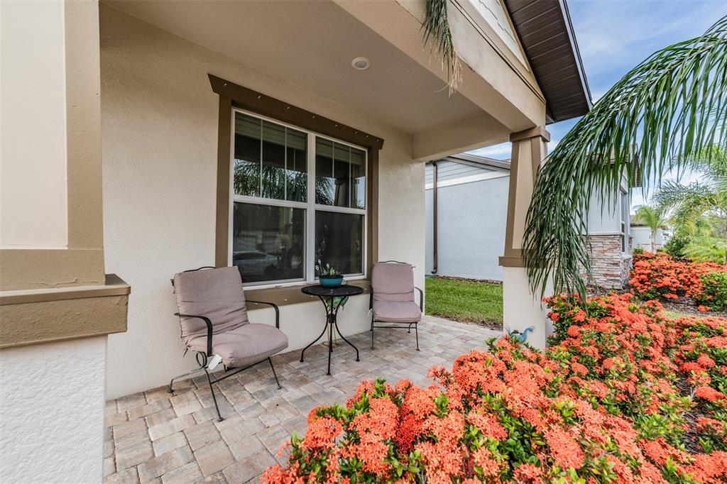 A covered front porch features two chairs, a small table, and vibrant orange flowers — 2836 BUCKHORN FOREST DRIVE, VALRICO, FL