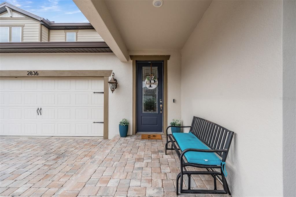 A paved entryway features a dark blue front door, a metal bench, and a garage — 2836 BUCKHORN FOREST DRIVE, VALRICO, FL