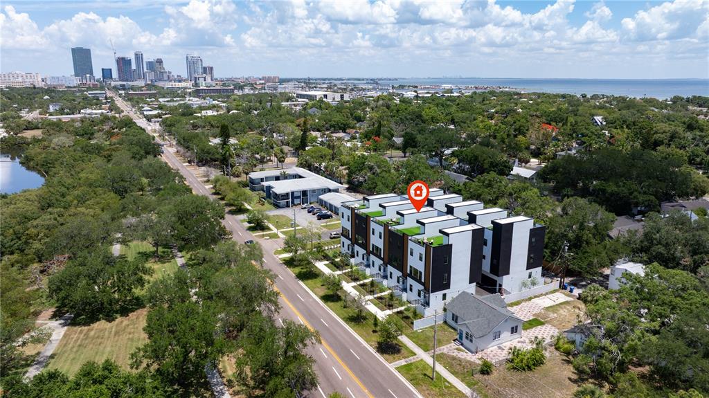 An aerial view shows a modern multi-unit townhouse complex with rooftop terraces near a city — 2104 4TH STREET S UNIT 3, ST PETERSBURG, FL