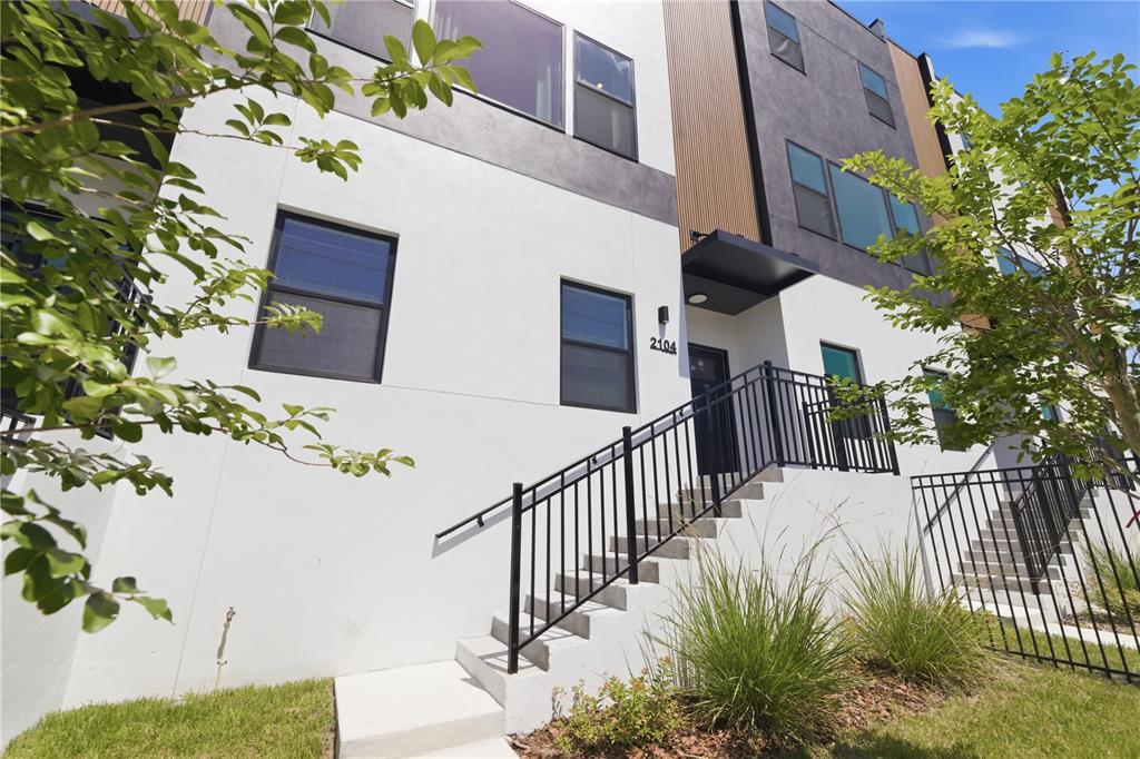 A modern multi-story townhouse exterior features white stucco, dark accents, and a front staircase — 2104 4TH STREET S UNIT 3, ST PETERSBURG, FL