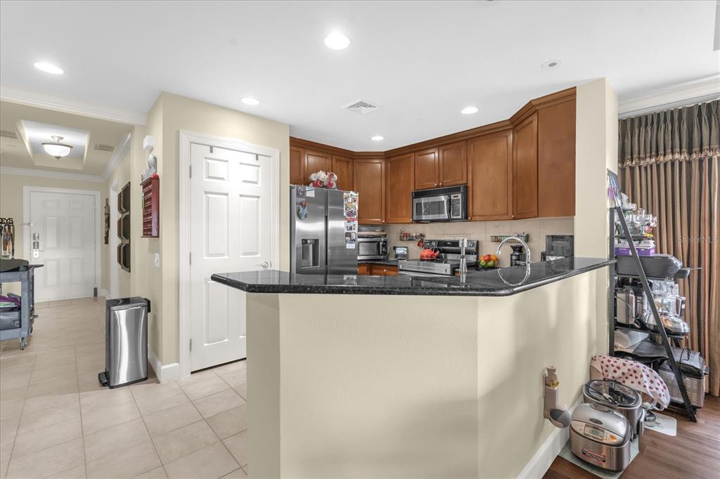 A kitchen features wood cabinets, a black granite countertop, and stainless steel appliances — 1364 CENTRE COURT RIDGE DRIVE UNIT 101, REUNION, FL