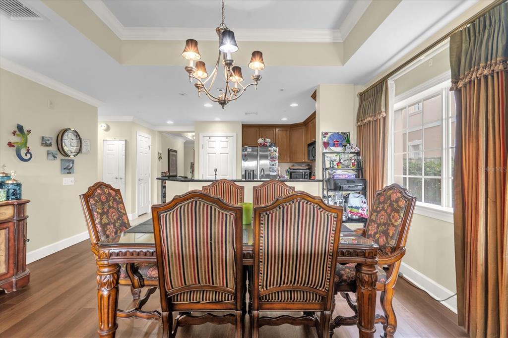 A dining room with a glass-topped table and six chairs sits before an open kitchen — 1364 CENTRE COURT RIDGE DRIVE UNIT 101, REUNION, FL