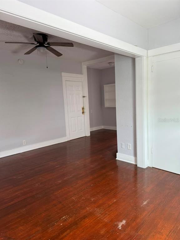 An interior view shows a room with hardwood floors, a ceiling fan, and white trim — 308 GROVE STREET N UNIT 205, ST PETERSBURG, FL