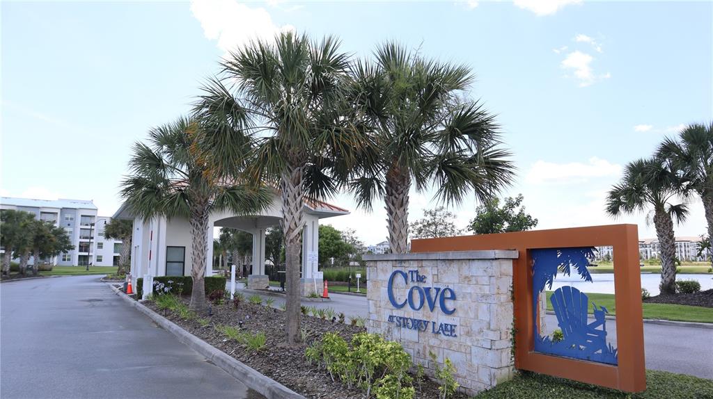 The entrance to The Cove at Storey Lake features a stone sign and palm trees — 3120 PARADOX CIRCLE UNIT 205, KISSIMMEE, FL