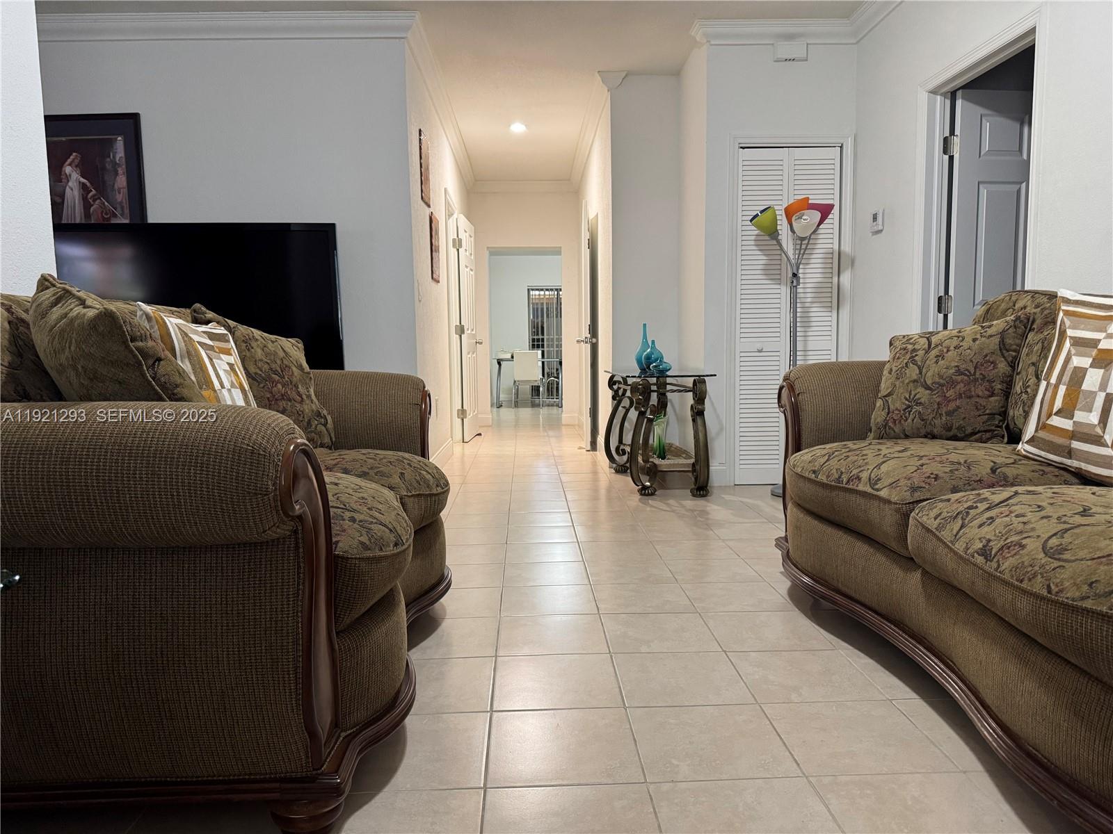 A hallway with tile flooring connects two living areas featuring matching brown patterned sofas — 3041 NW 95th Ter, Miami FL 33147, MIAMI, FL