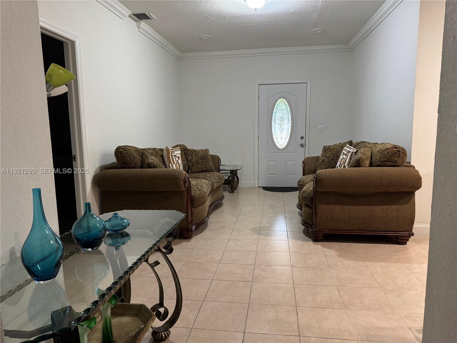 A living room with two brown sofas, a glass console table, and tile flooring — 3041 NW 95th Ter, Miami FL 33147, MIAMI, FL