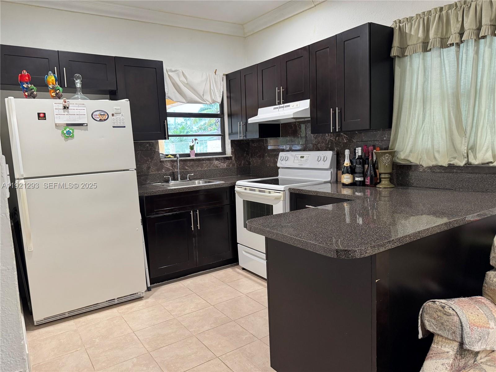 A kitchen features dark wood cabinets, granite countertops, a white refrigerator, and a white stove — 3041 NW 95th Ter, Miami FL 33147, MIAMI, FL