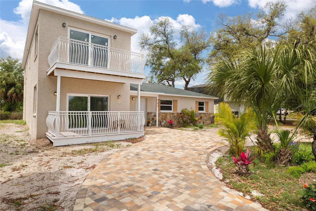 A two-story house with a paved driveway, white railings, and a stone-accented exterior wall — 743 BAYSHORE DRIVE, TARPON SPRINGS, FL