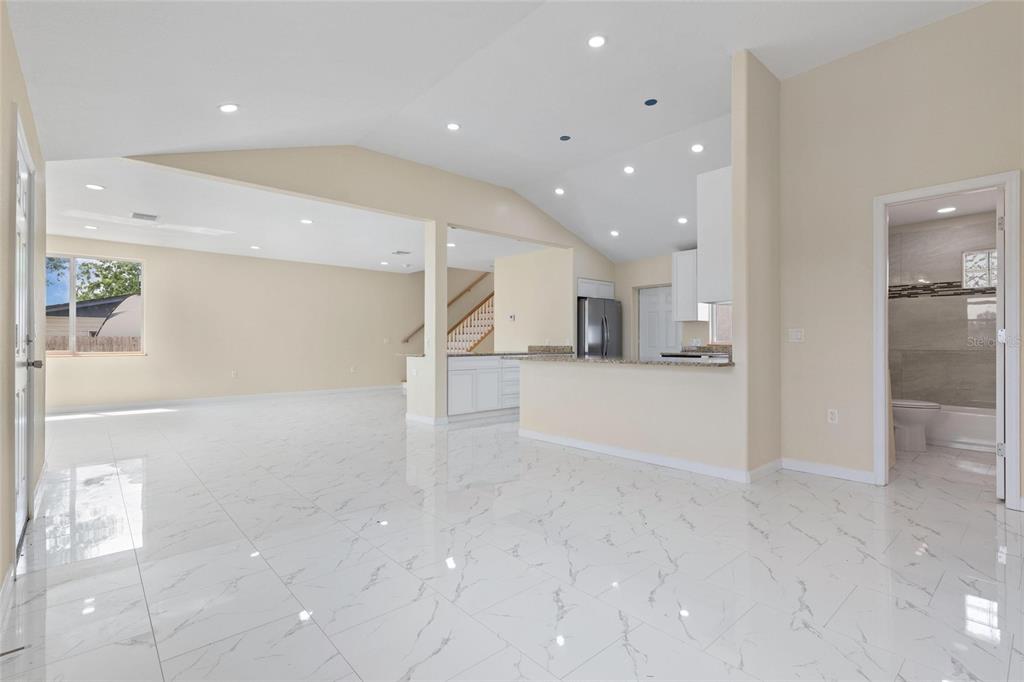 An open-concept living area features white marble-look tile flooring, vaulted ceilings, and a kitchen island — 743 BAYSHORE DRIVE, TARPON SPRINGS, FL