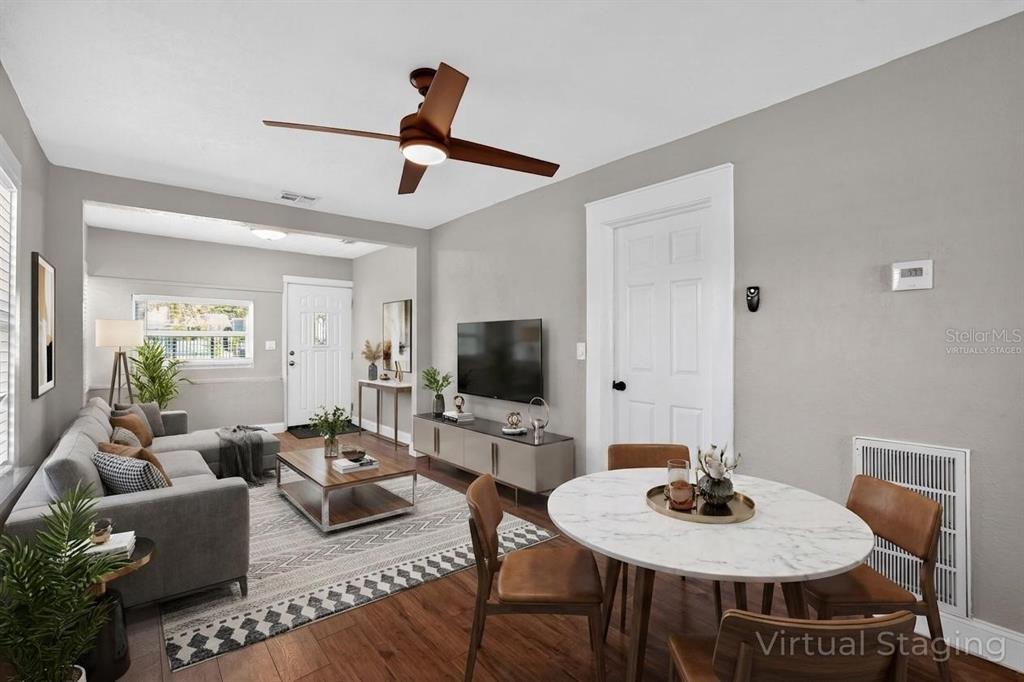 This virtually staged living and dining area features gray walls, wood flooring, and a ceiling fan — 3250 PRESCOTT STREET N, ST PETERSBURG, FL