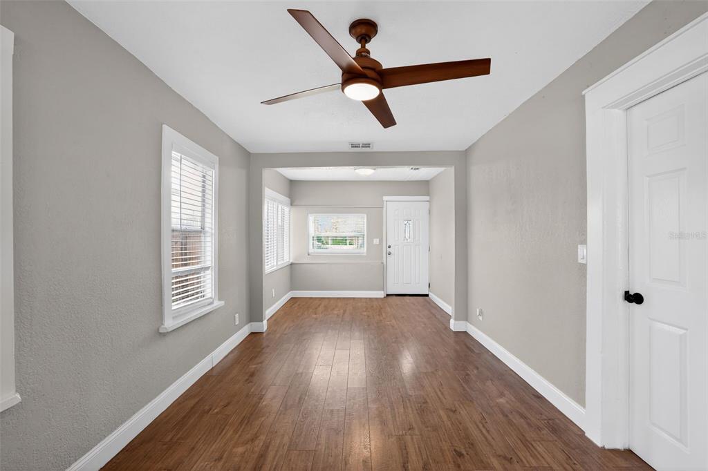 An empty room with wood-look flooring, gray walls, a ceiling fan, and a white door — 3250 PRESCOTT STREET N, ST PETERSBURG, FL