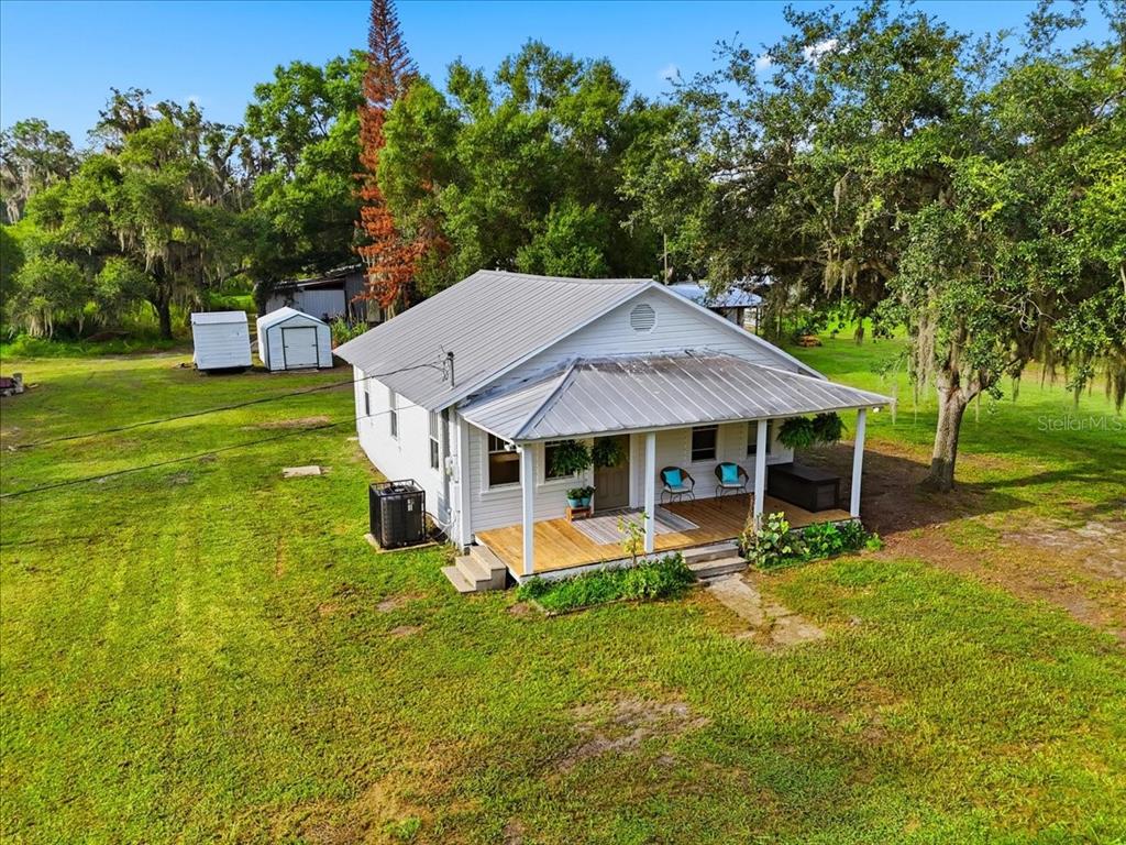 A white house with a metal roof and a wooden porch sits on a grassy lot — 4919 E COUNTY ROAD 542, LAKELAND, FL