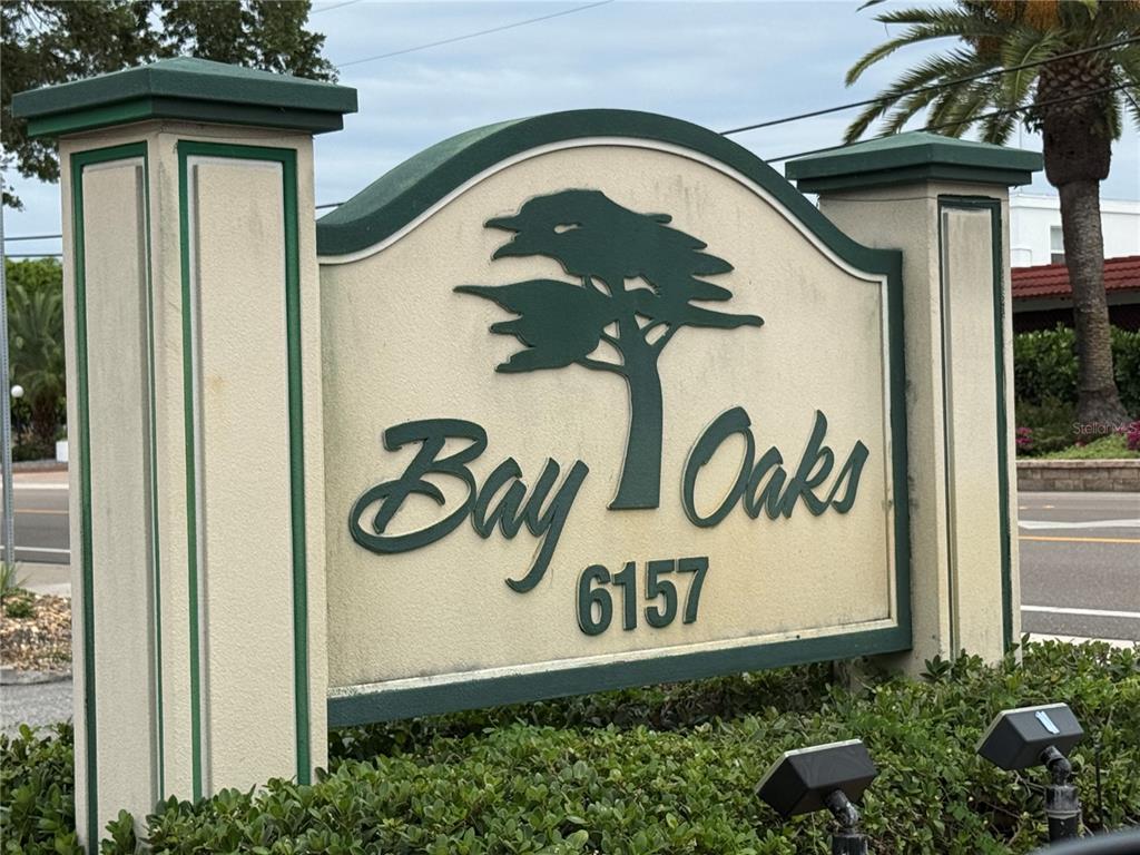 A monument sign for Bay Oaks stands outdoors surrounded by green landscaping — 6157 MIDNIGHT PASS ROAD UNIT F22, SARASOTA, FL