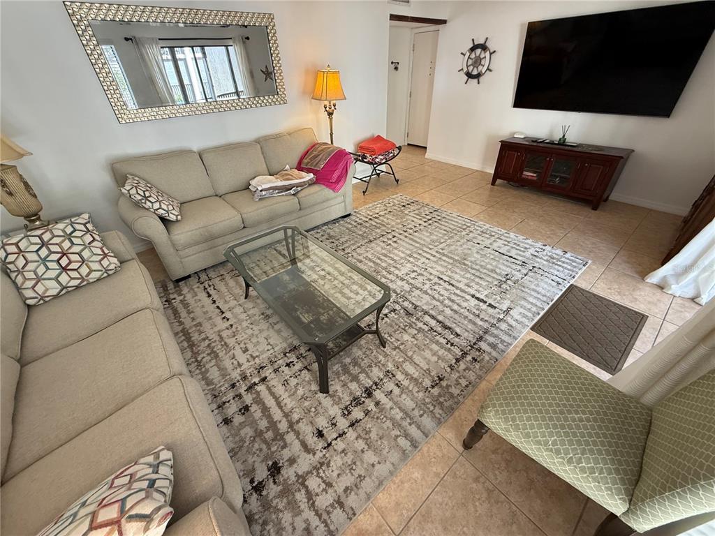 A living room features two beige sofas, a glass coffee table, and a large area rug — 6157 MIDNIGHT PASS ROAD UNIT F22, SARASOTA, FL