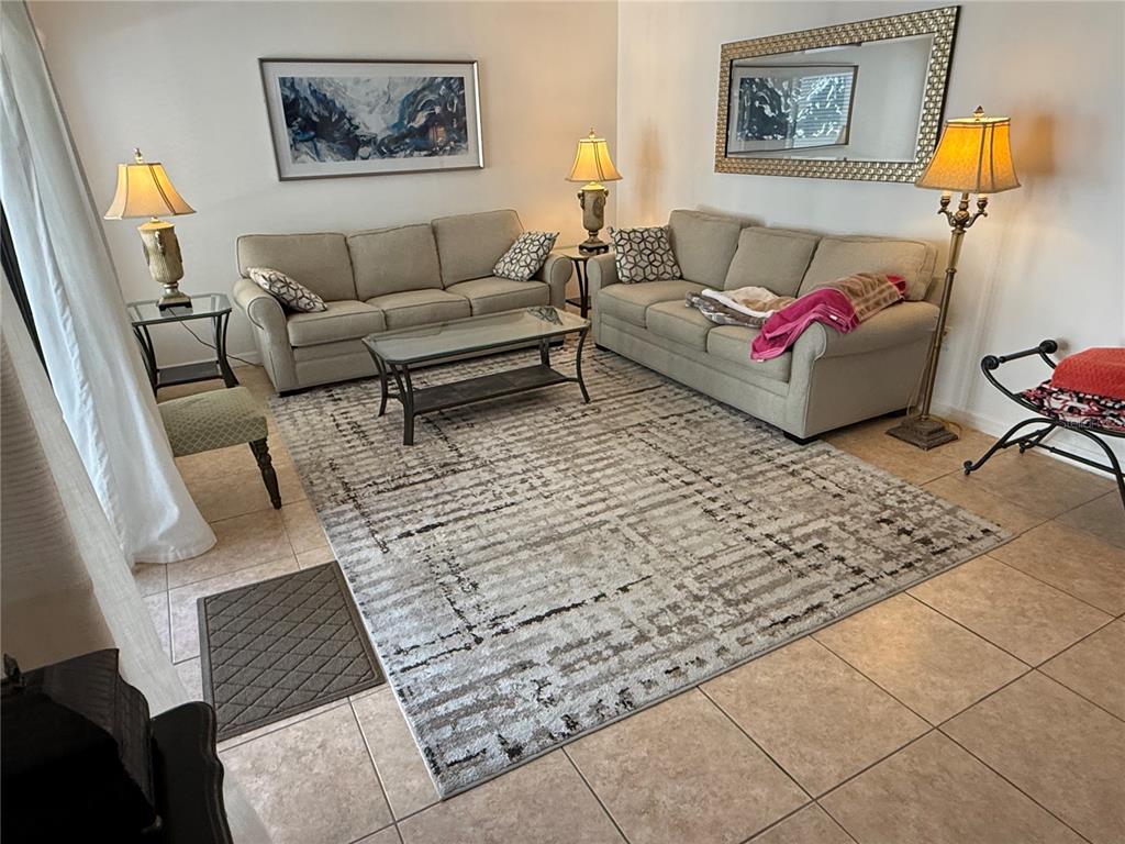 A living room features two beige sofas, a glass coffee table, and a patterned rug — 6157 MIDNIGHT PASS ROAD UNIT F22, SARASOTA, FL